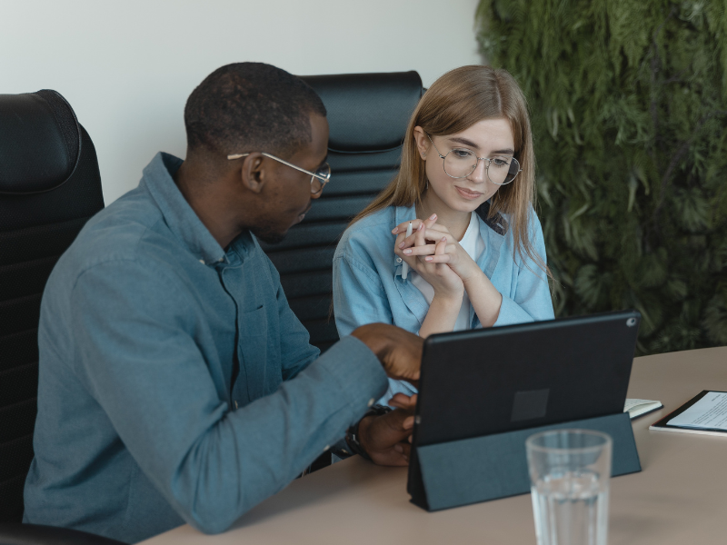 Man teaching a woman sitting beside him using a tablet